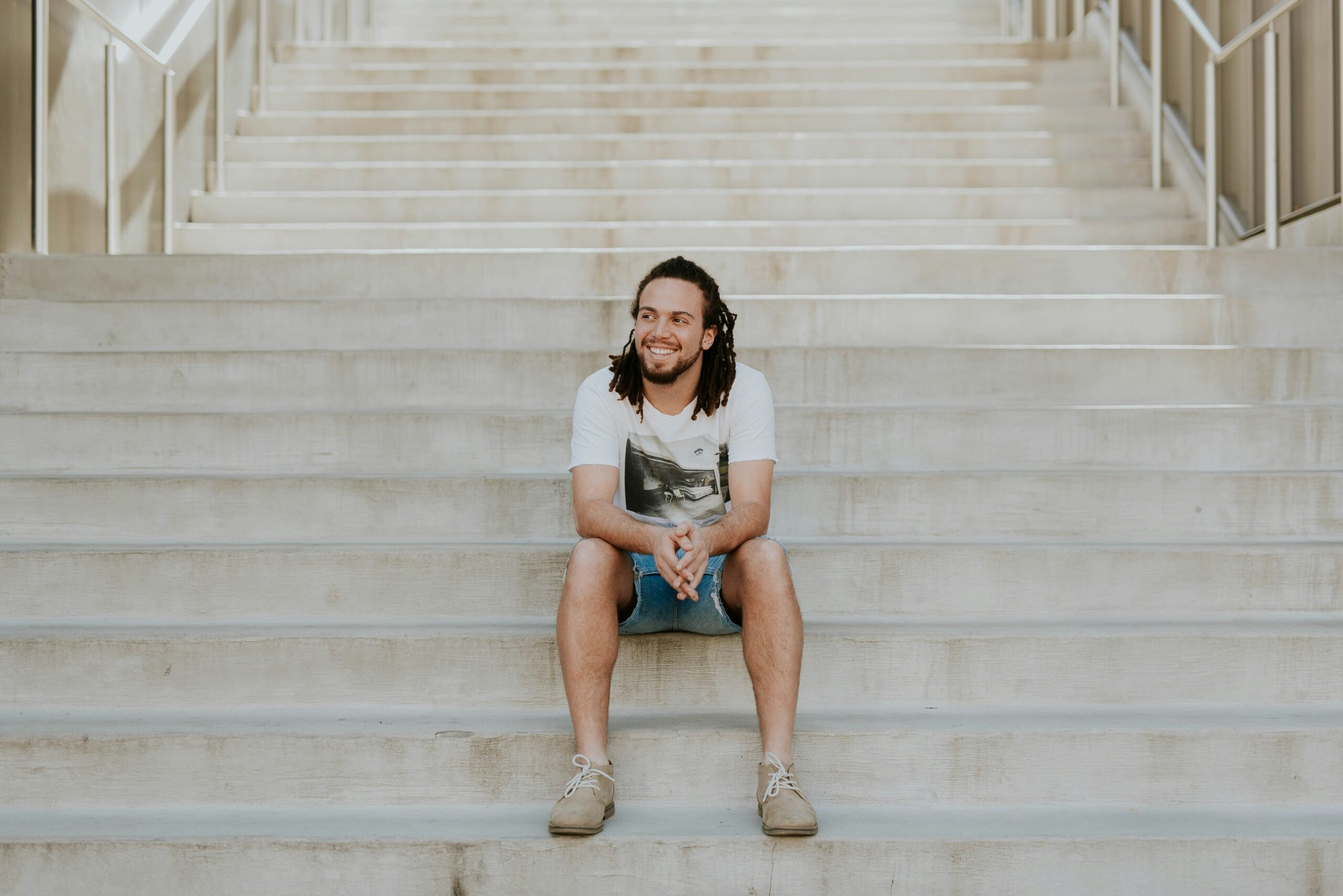 Mixed race man sitting on steps, smiling, taking care of his mental health