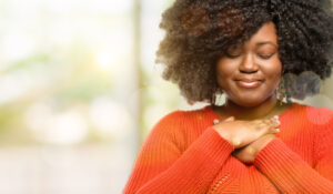 A Black woman with hands in heart, expressing love and health concep
