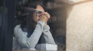 Person side view, Asian Women sad, broken heart and depressed about a bad relationship.Young thoughtful girl sitting alone and negative thinking in a coffee shop.Depressed and thoughtful concept.