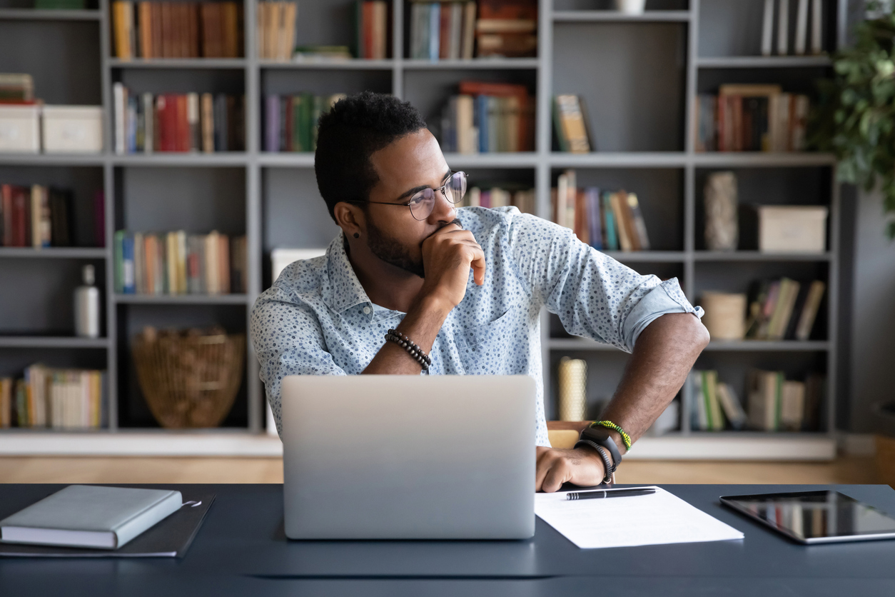 Black man contemplating at laptop. Feeling anxious about election