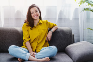 Smiling young woman relaxing while sitting on comfortable couch in therapy for anxiety
