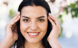 Image of a woman holding her hair back, smiling. 