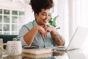 Smiling Black woman using laptop. Managing ADHD 