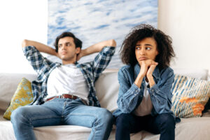 Image of a couple on a couch, sitting with conflict. 