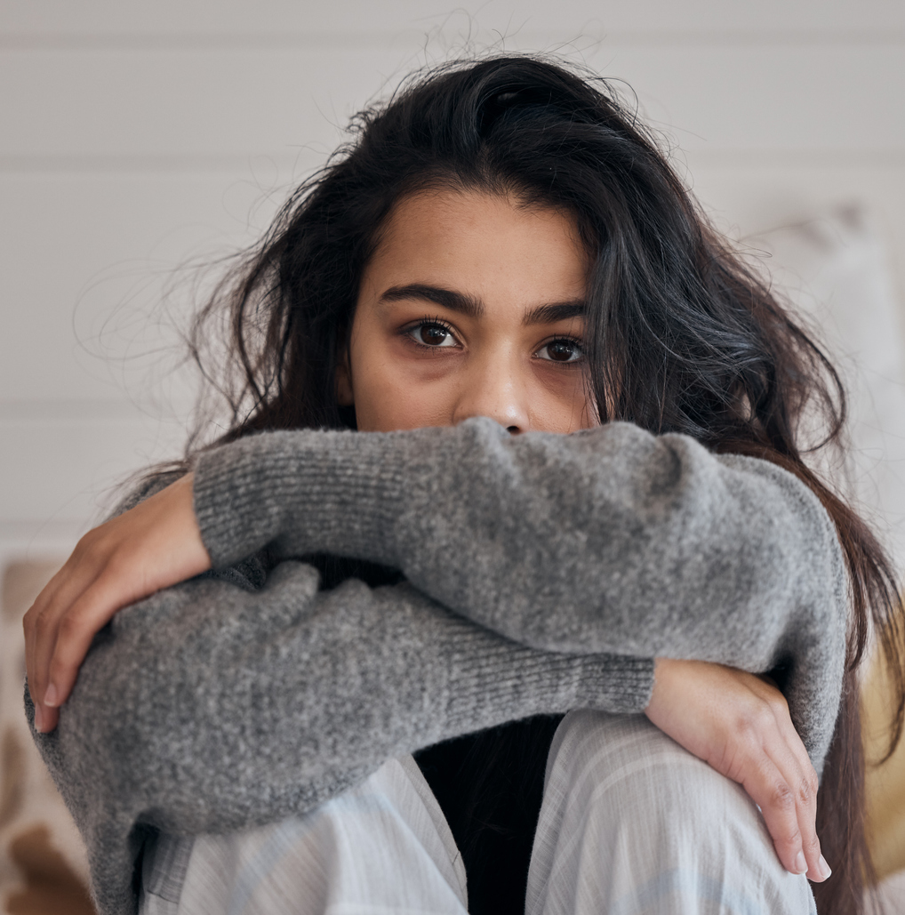 Female sitting with knees to chest, arms wrapped around knees, feeling anxious about the election