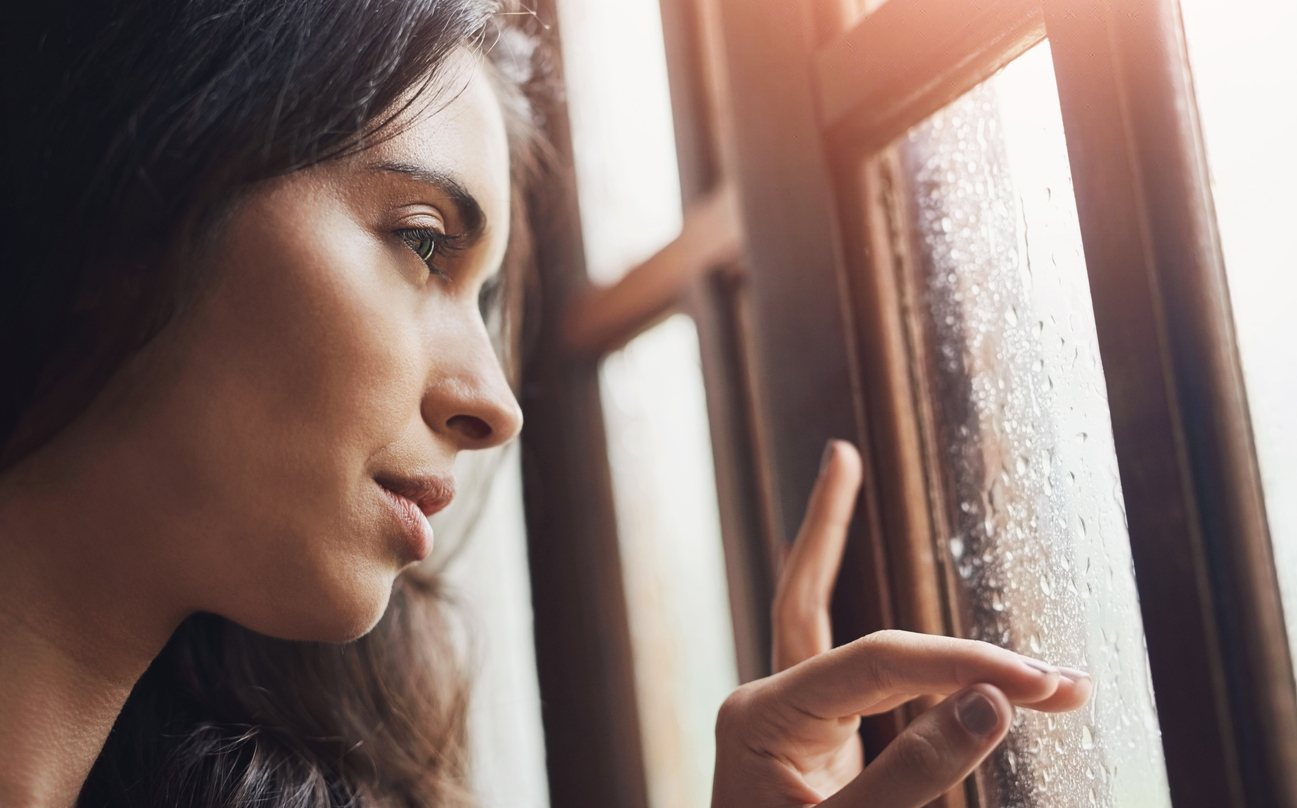 Female looking out the window at the rain, wanting to get out of the darkness of depression