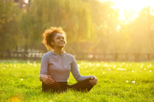 Person sitting outside with sun on their face, smiling, feeling calm while practicing Polyvagal exercises