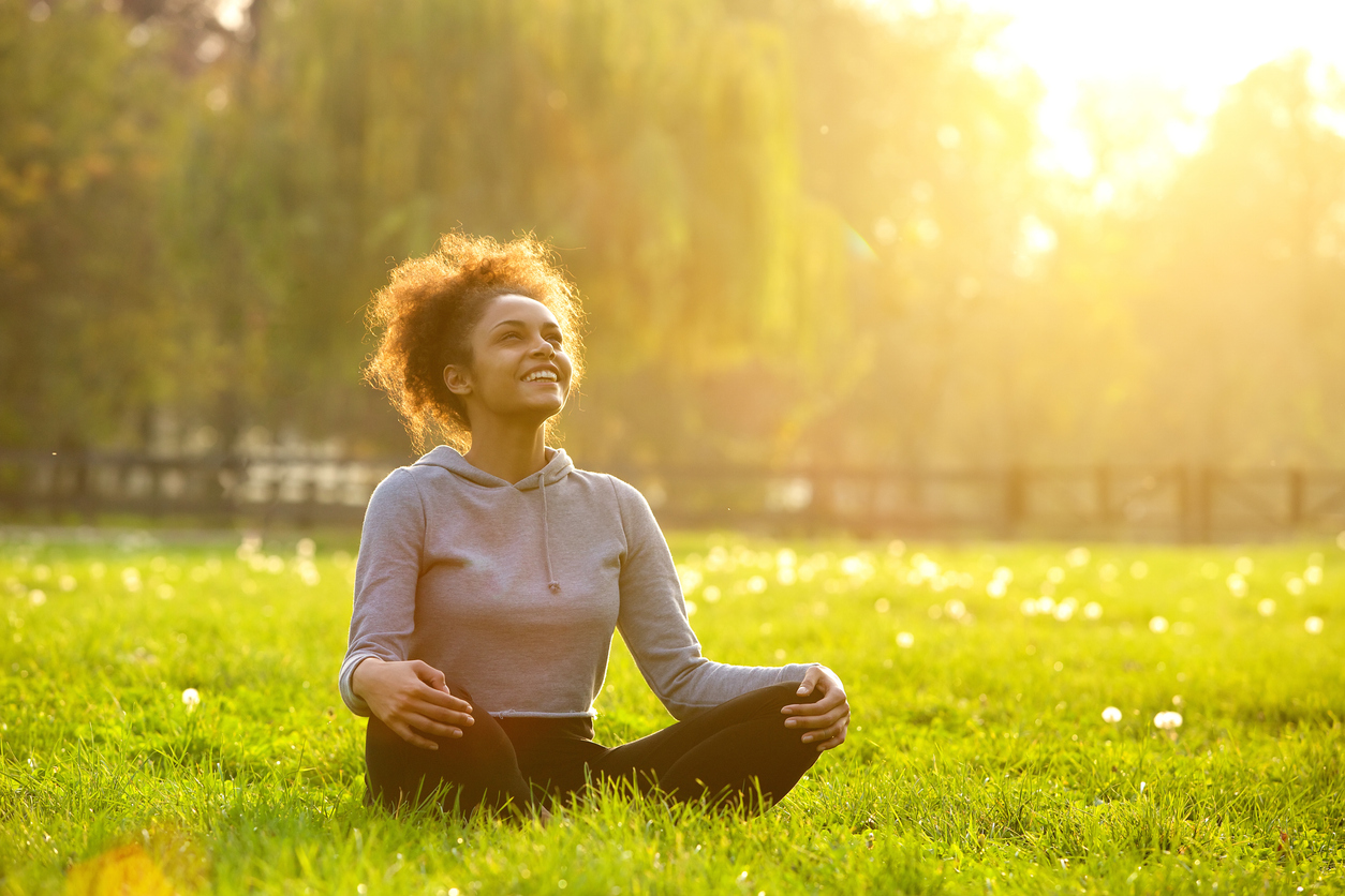 Person sitting outside with sun on their face, smiling, feeling calm while practicing Polyvagal exercises