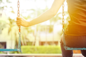 Woman holding empty swing while swinging in the park in the morning