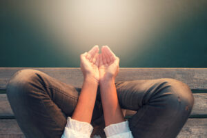 Image of a person sitting with hands cupped receiving calmness through light