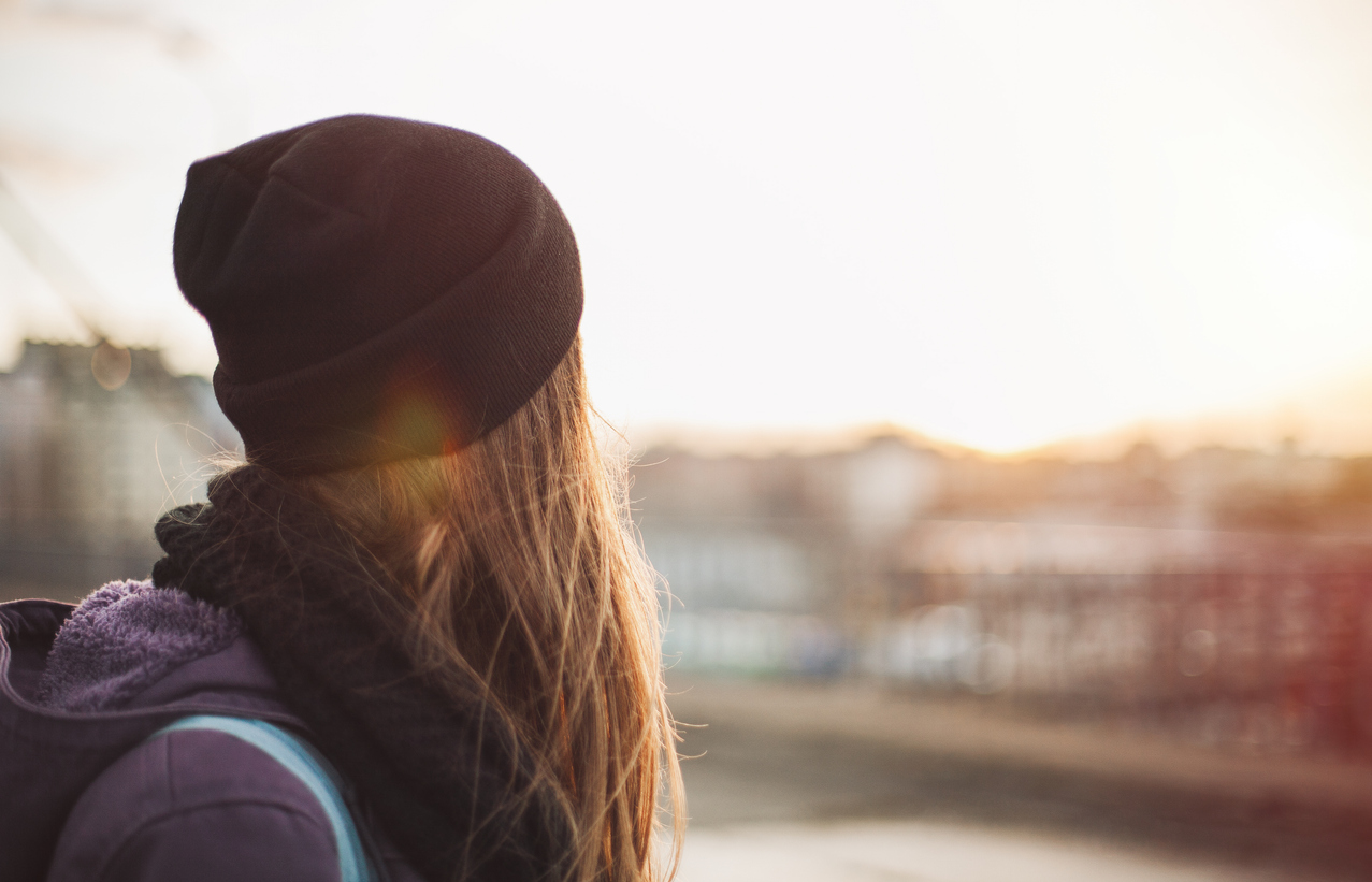 Girl with long har and hat looking in the distance, feeling less anxious