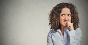 Image of a woman biting her thumbnail, anxious.