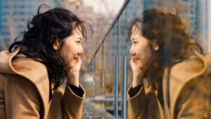 Image of a girl looking at her mirror image in glass.