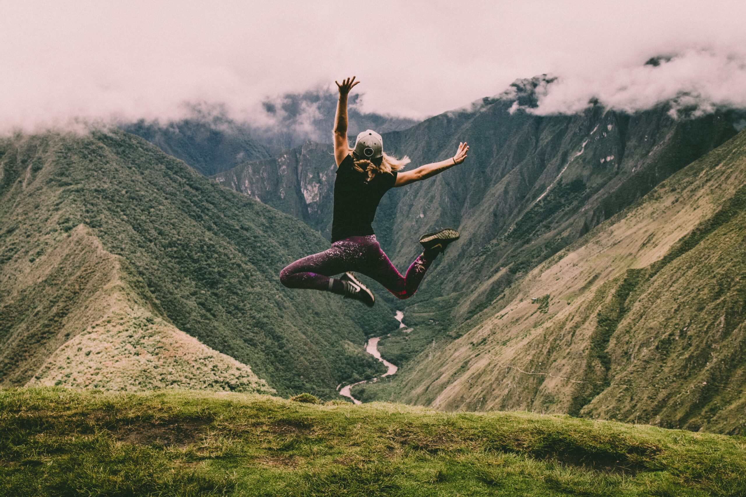 Person jumping for joy on a mountain top. Learning to experience joy.