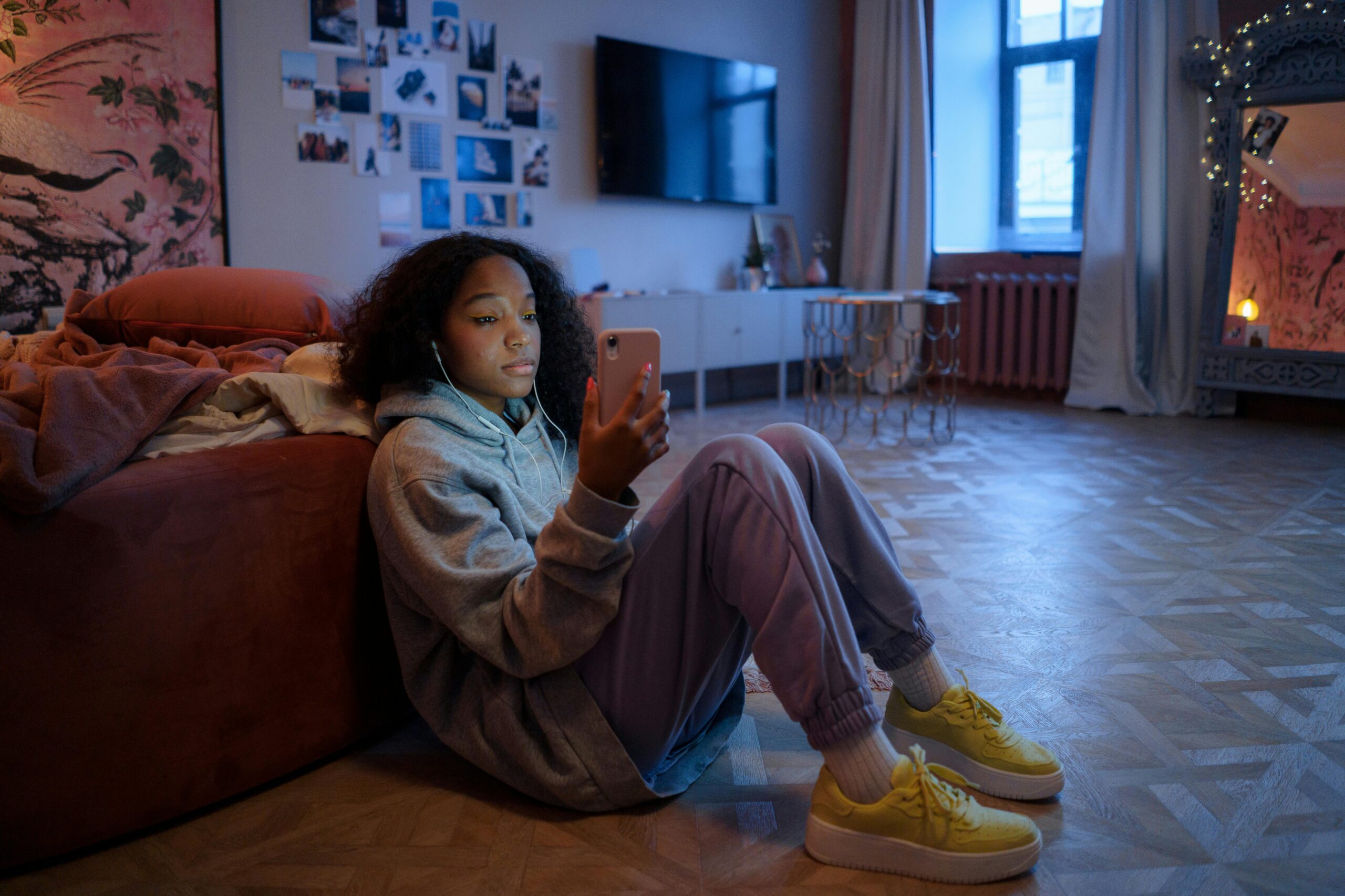 Teen in bedroom on floor looking at social media on phone