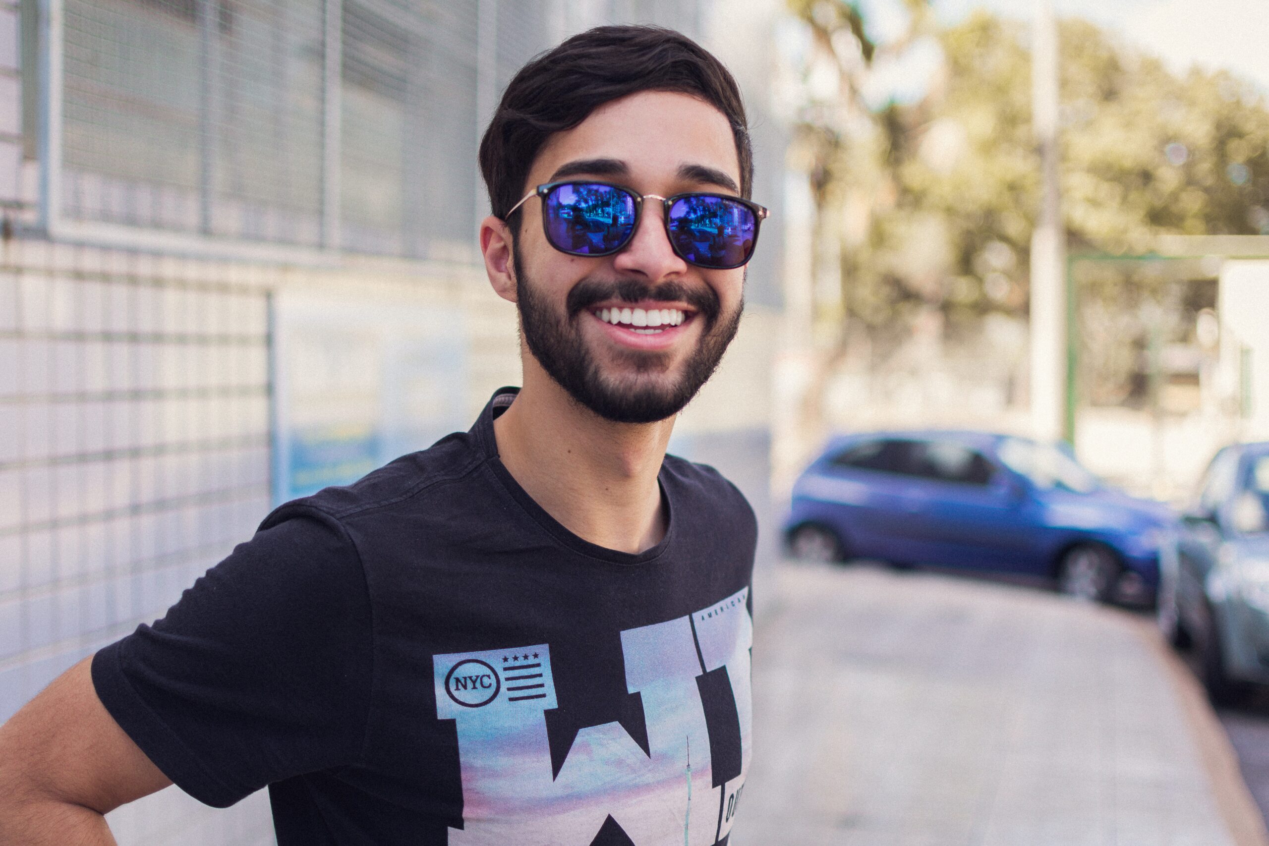 Young man with sunglasses, smiling on a nice day in the city, outside.
