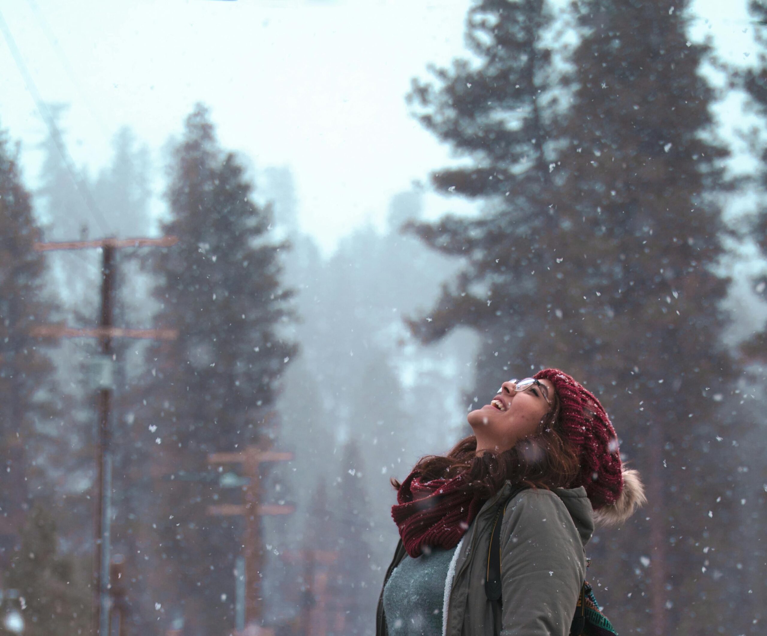 Person outside in the snow, embracing the cold and snow on their face with a smile, Taking care of their mental health during the winter months