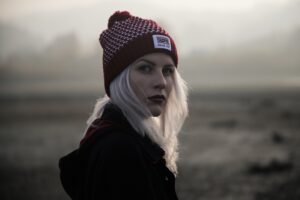 Image of a woman with white/blonde hair outside in a misty environment with a winter hat on.