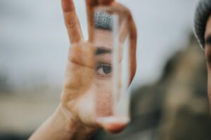 Person looking at self in a piece of glass. Reflecting on their relationship with themselves.