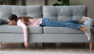 Image of a girl face down on a couch feeling depressed, wanting help.